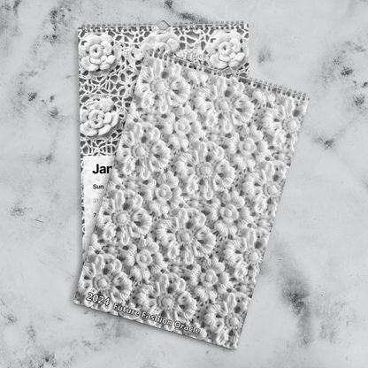 A white and black lace Crochet Patterns Wall Calendar: A Year-Round Inspiration for Crochet Enthusiasts on a marble surface, perfect for crochet enthusiasts looking for handmade crochet patterns or a crochet calendar.