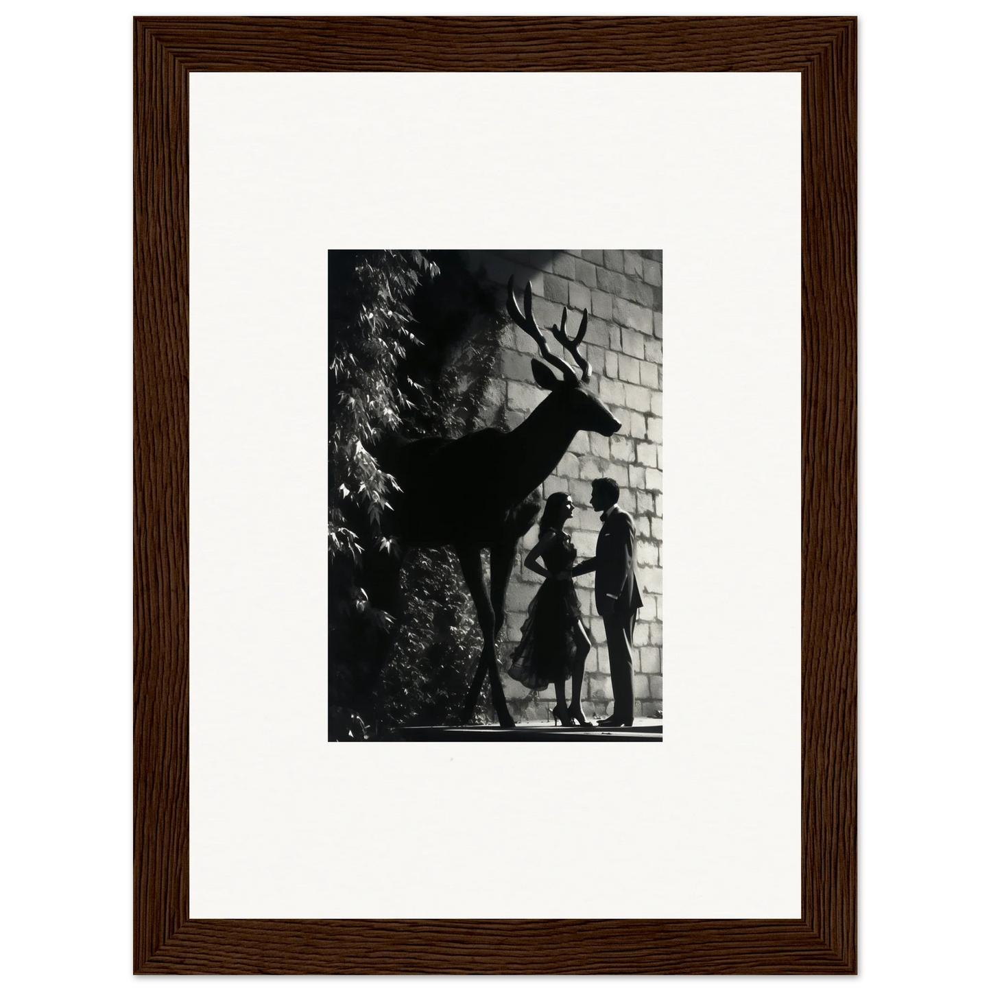 Framed black and white photograph showing silhouettes of a deer and two people against a wall.