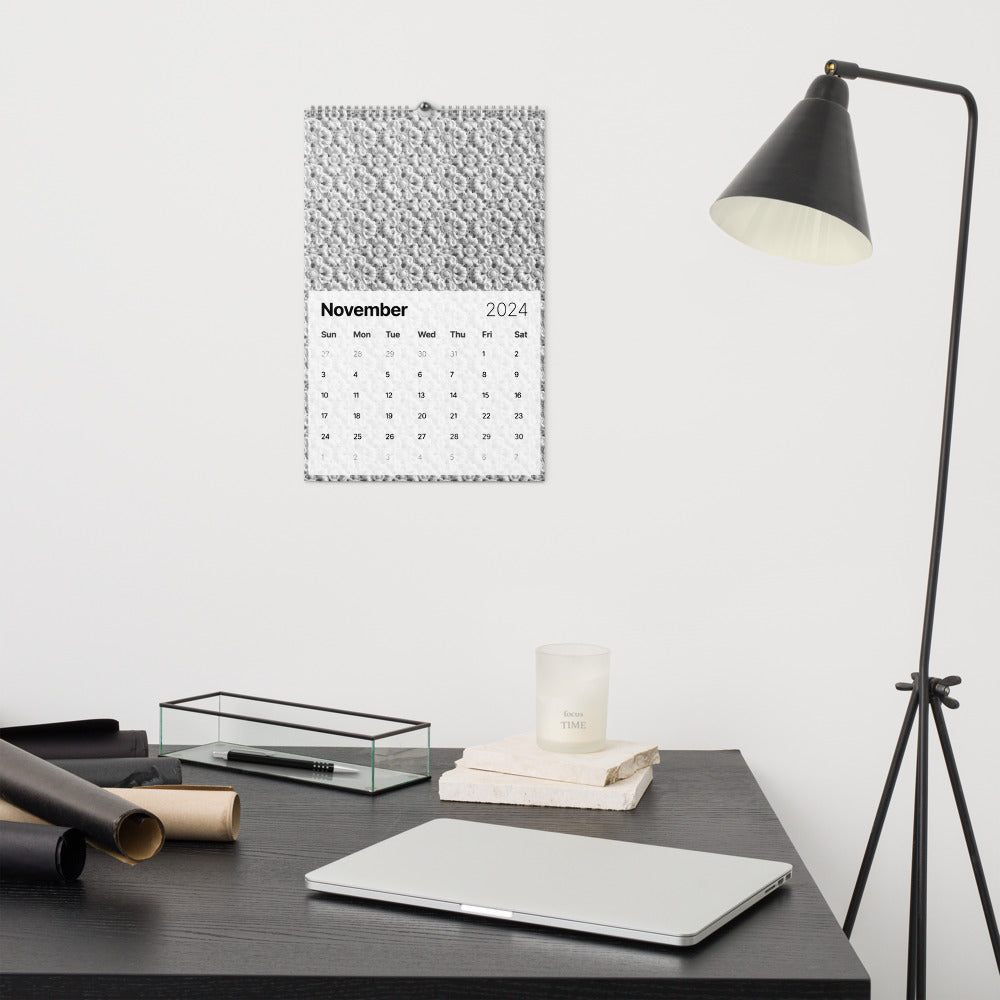 The modified version of the text will read: "A desk adorned with the 2024 Crochet Patterns Wall Calendar: A Year-Round Inspiration for Crochet Enthusiasts, featuring crochet patterns and a lamp."