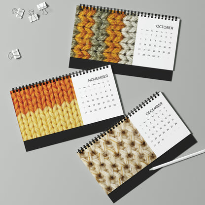 Three limited edition Crochet Addicts - 2024 desktop calendars on a table with pens and pencils.