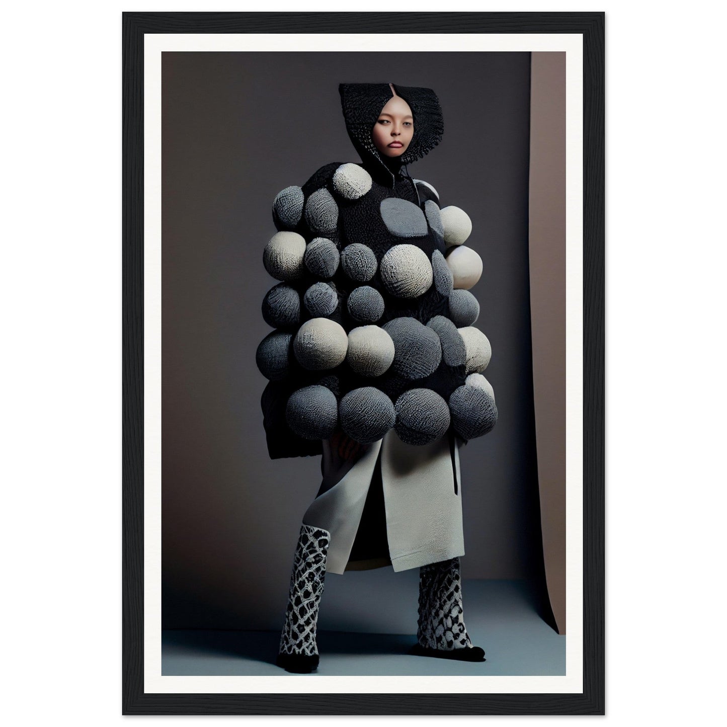 Avant-garde coat adorned with oversized spherical pom-poms in shades of gray and white.