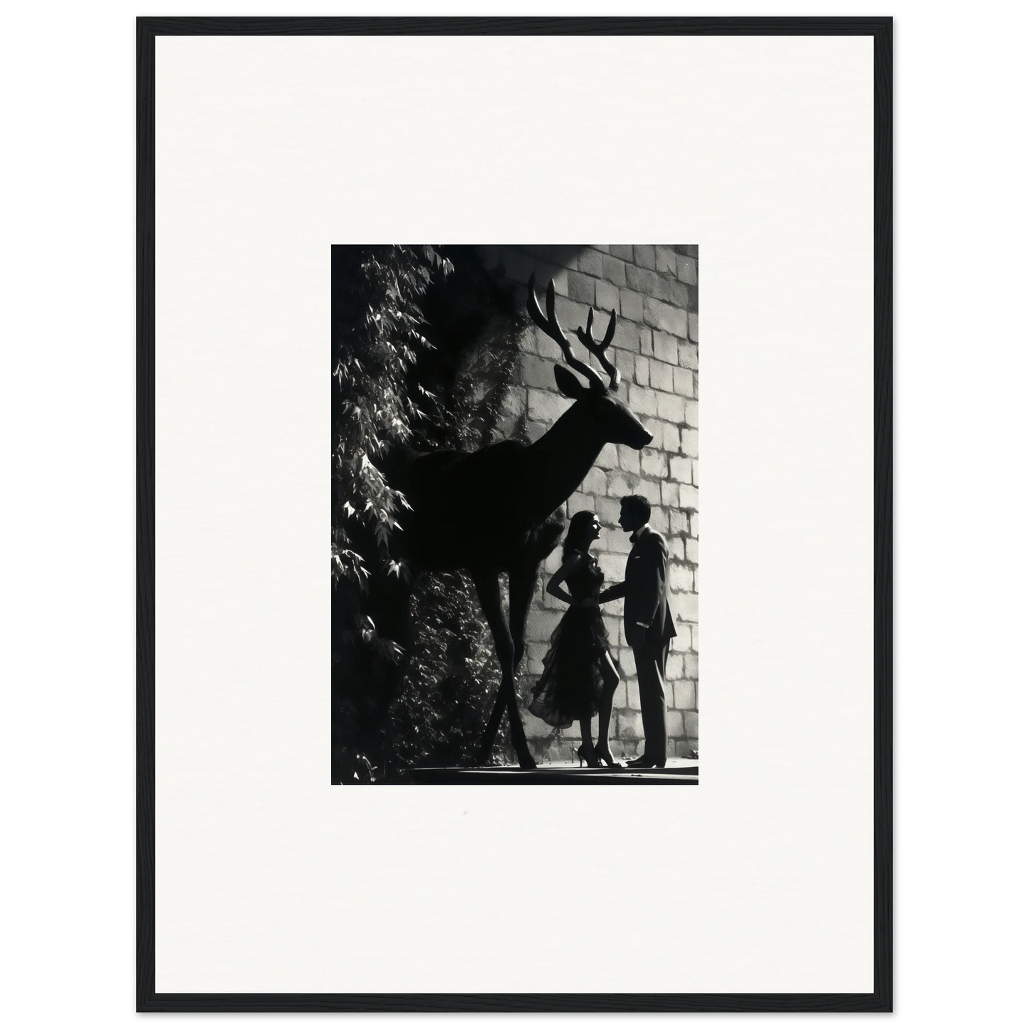 Black and white photograph of a deer’s shadow on a brick wall with two human silhouettes beneath it.