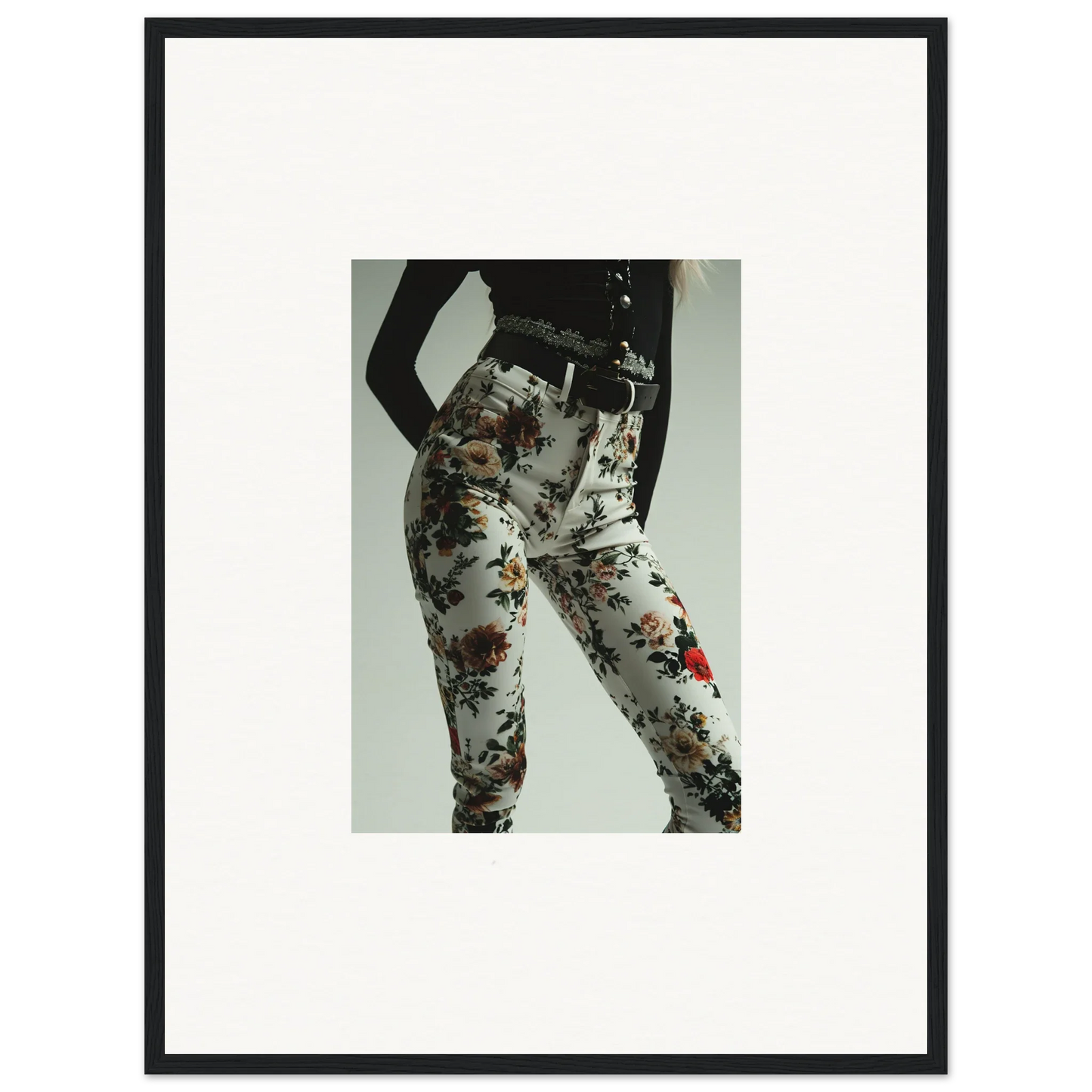 Framed black-and-white photograph of a person’s lower body wearing floral-patterned pants.