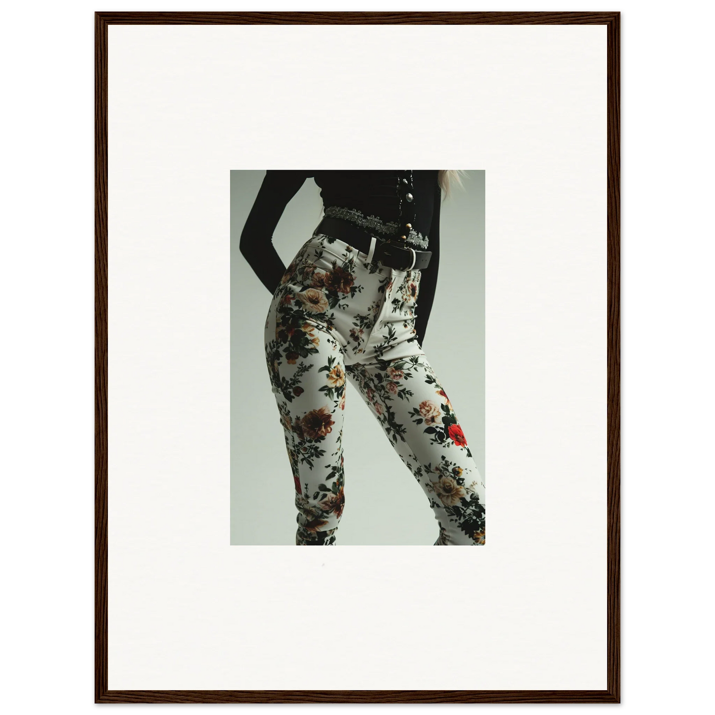 Framed black-and-white photograph showing a person’s lower body wearing floral-patterned pants.