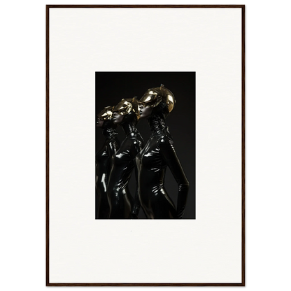 Framed photograph of three figures in shiny, dark outfits with metallic headpieces.