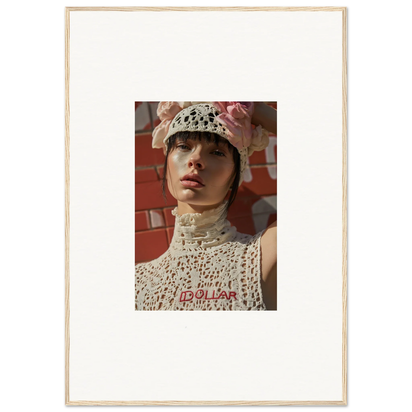 Portrait photograph of a person wearing a white crocheted hat and top with red lettering.