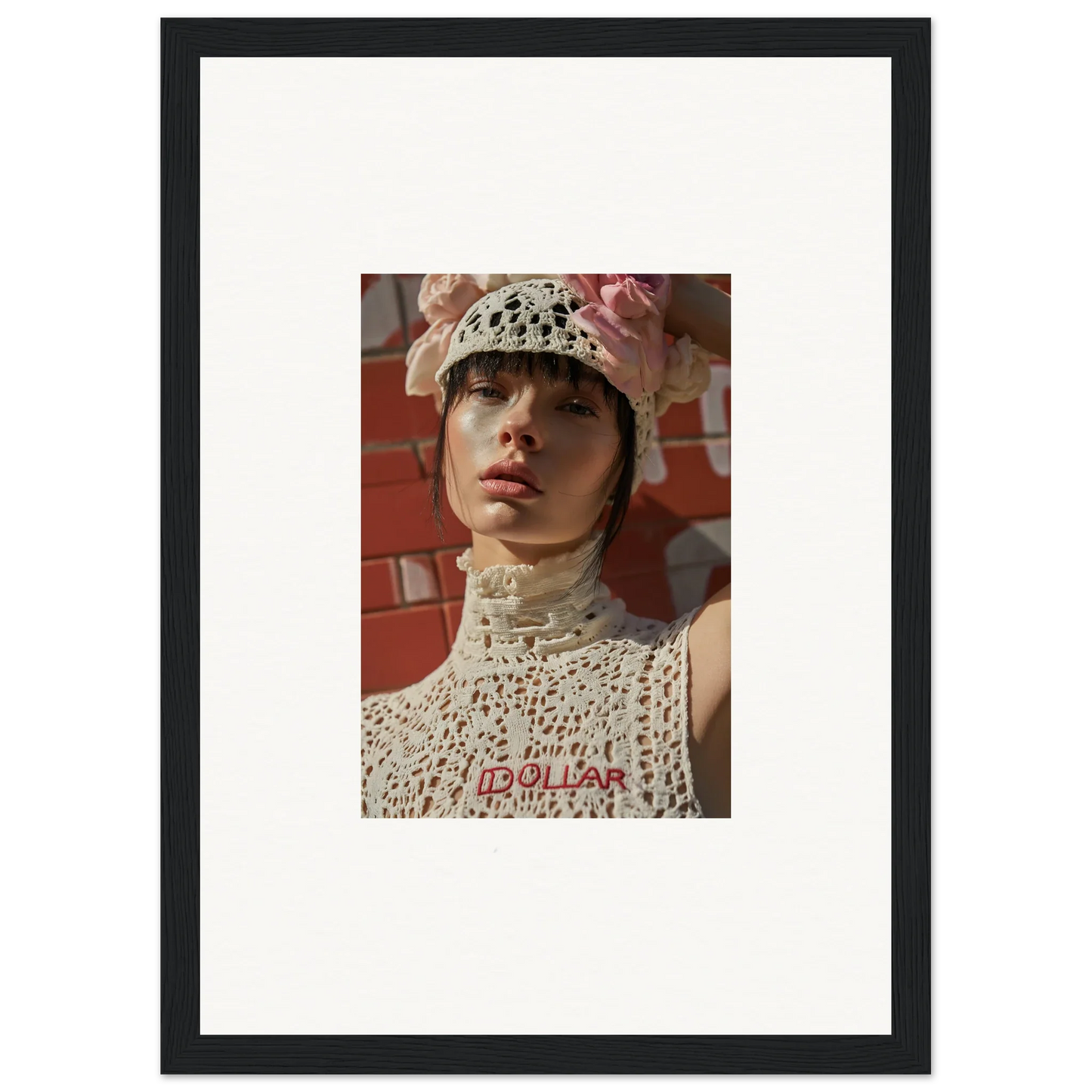 Framed portrait photograph of a person wearing a white crocheted hat and top against a reddish background.