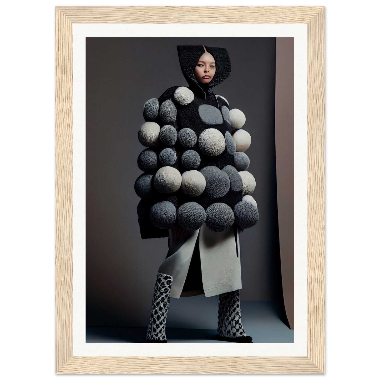 Avant-garde coat adorned with oversized spherical pom-poms in shades of gray and white.