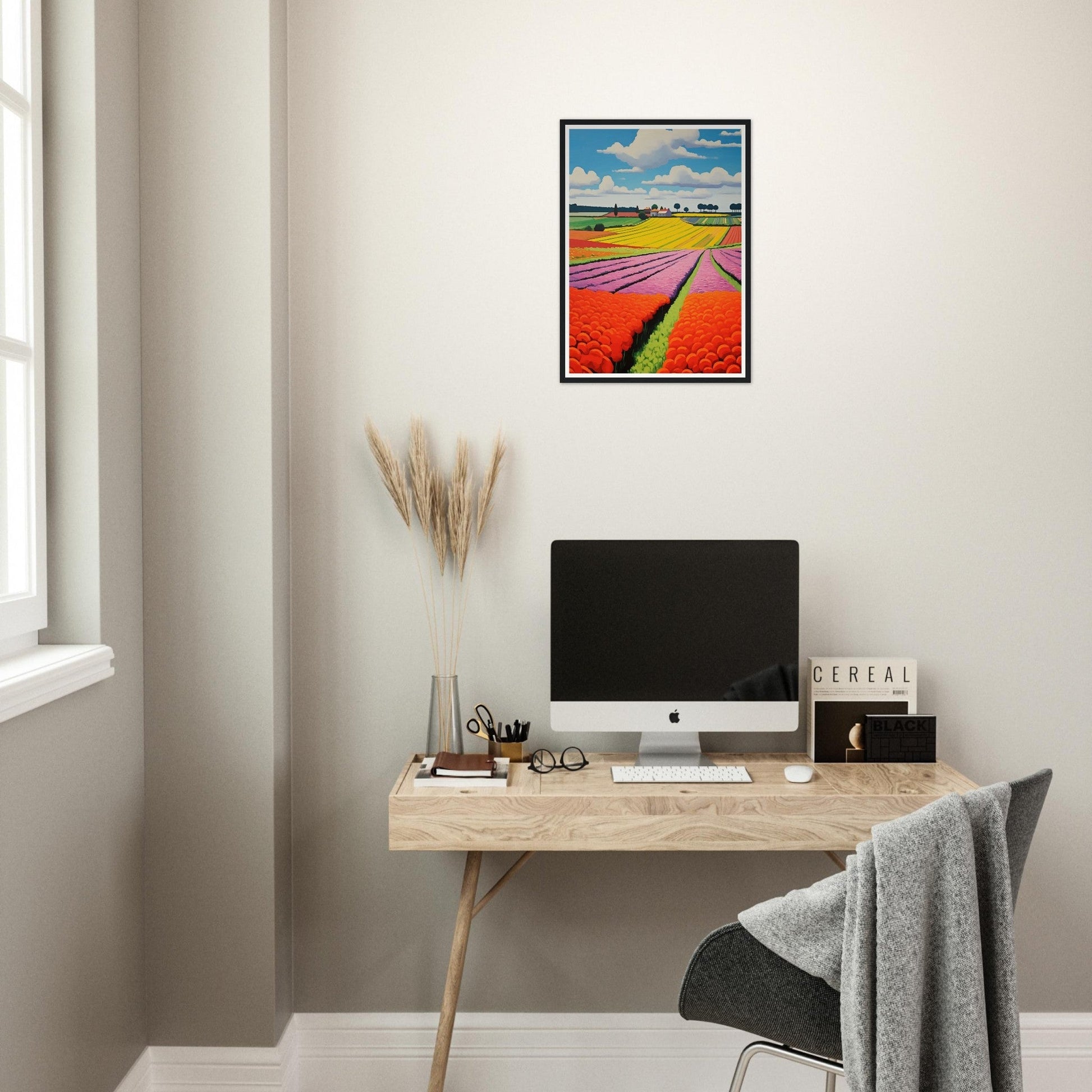 Minimalist workspace with a wooden desk, computer, and colorful wall art.