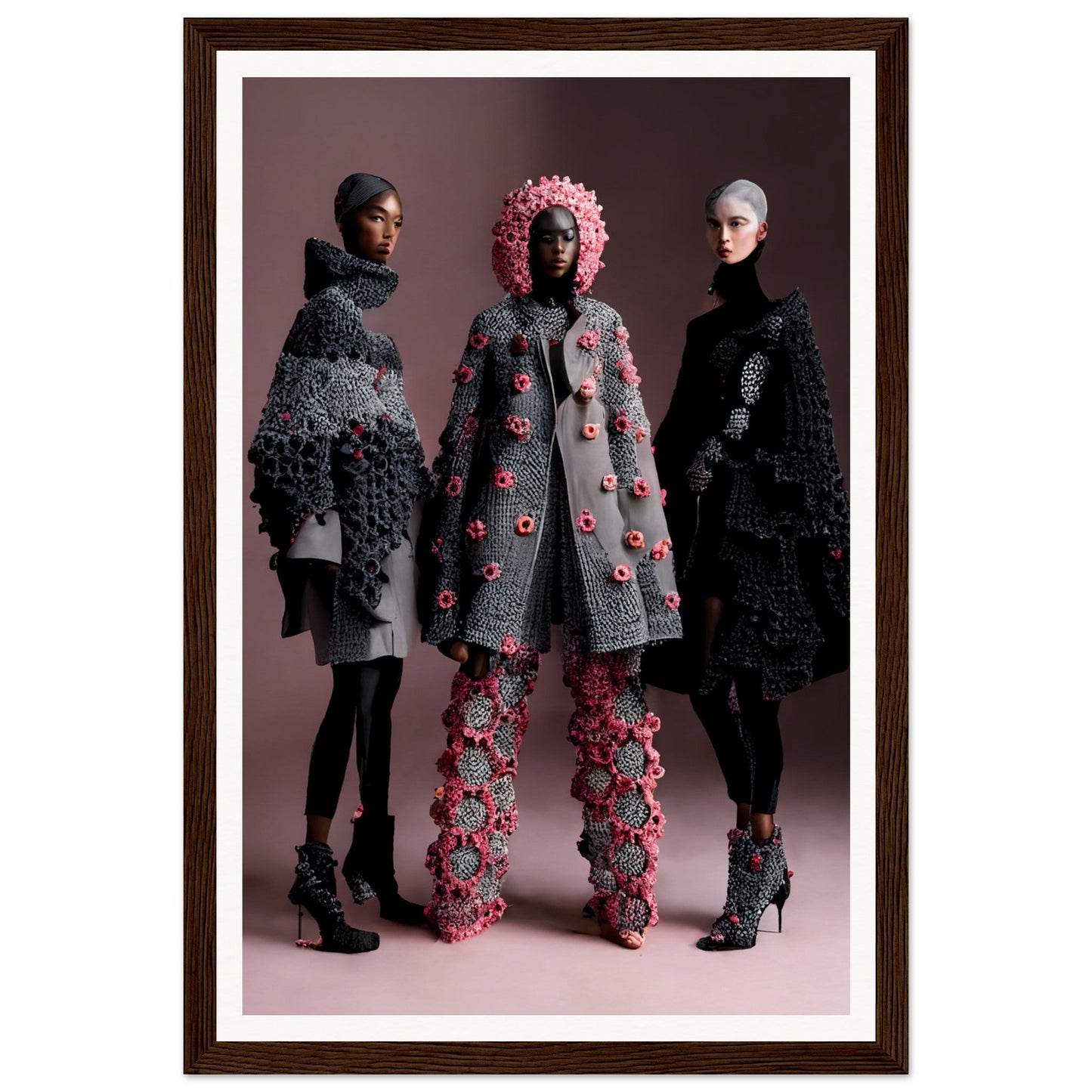 Framed photograph of three models wearing avant-garde, textured coats and accessories in gray and pink tones.