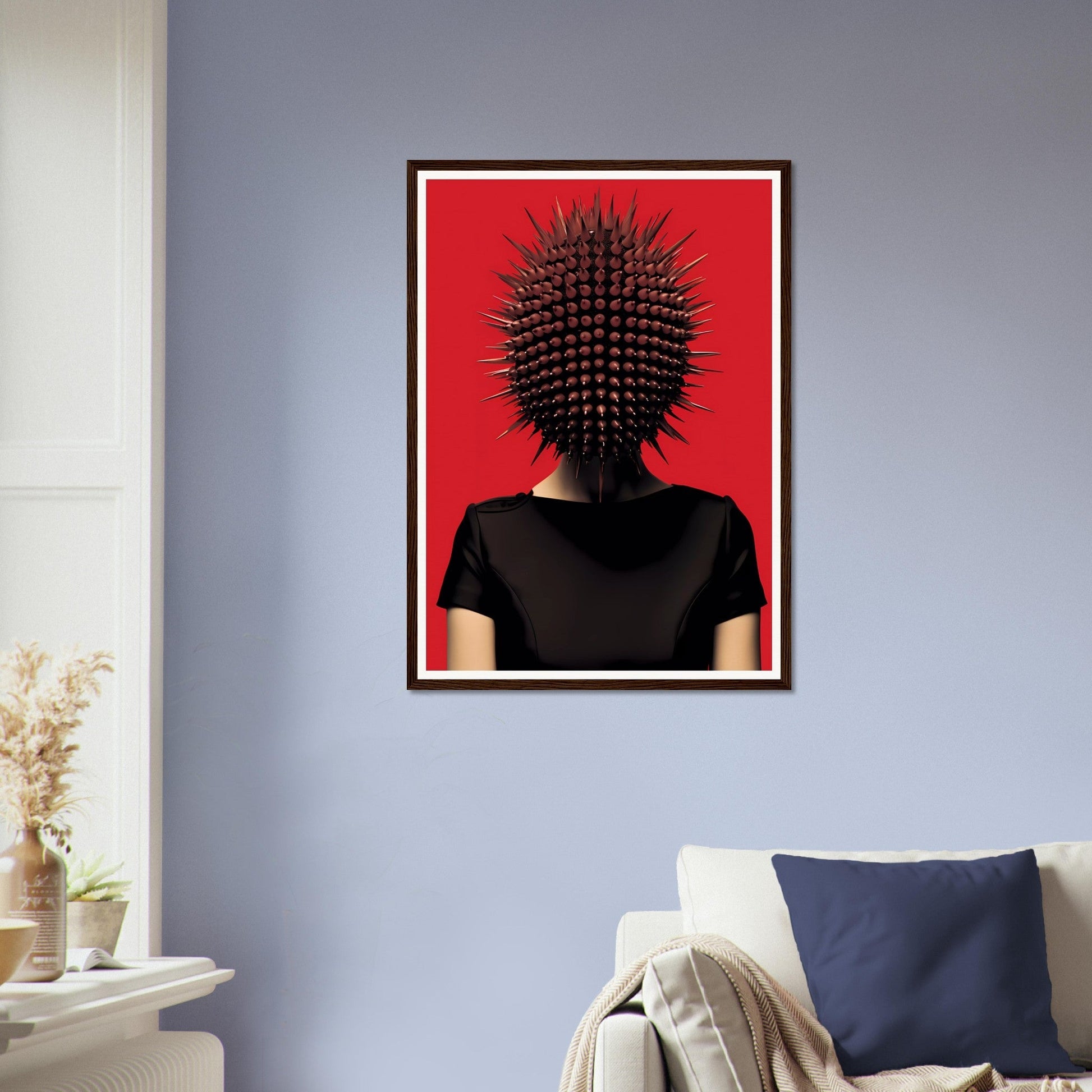 Framed artwork depicting a figure with a spiky, spherical object in place of a head against a red background.