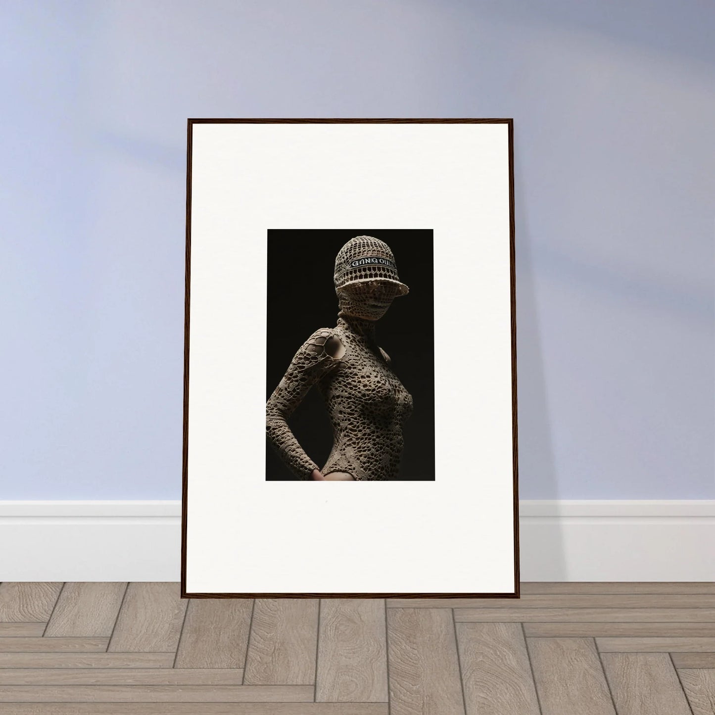 Framed black and white photograph of a figure covered in a textured, net-like material.