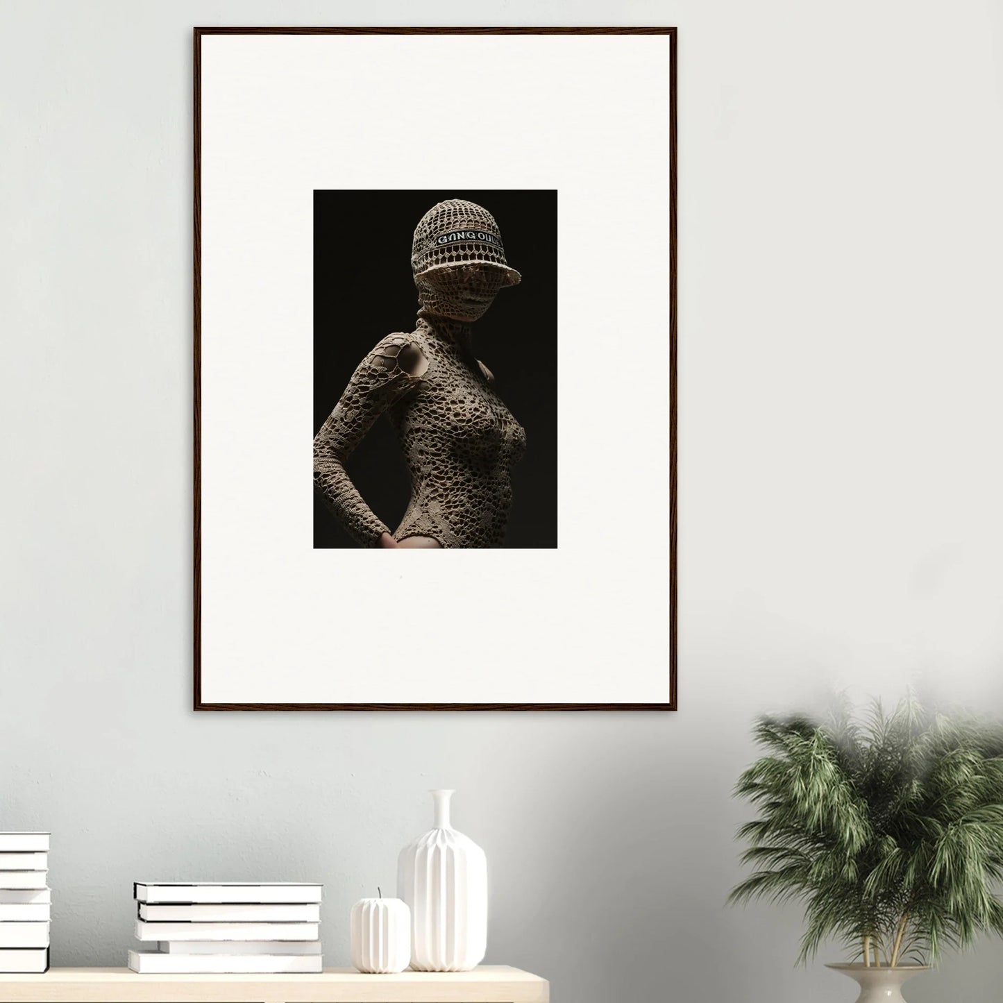 Framed black and white photograph of a figure wearing a textured bodysuit and hat.