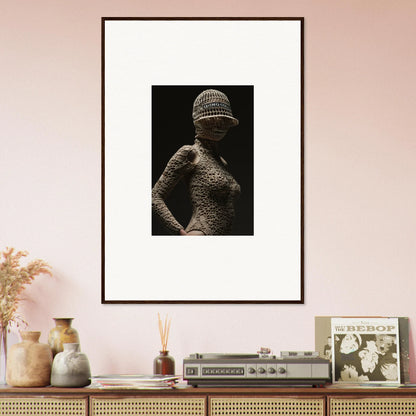 Framed black and white photograph of a figure wearing a textured bodysuit and hat.