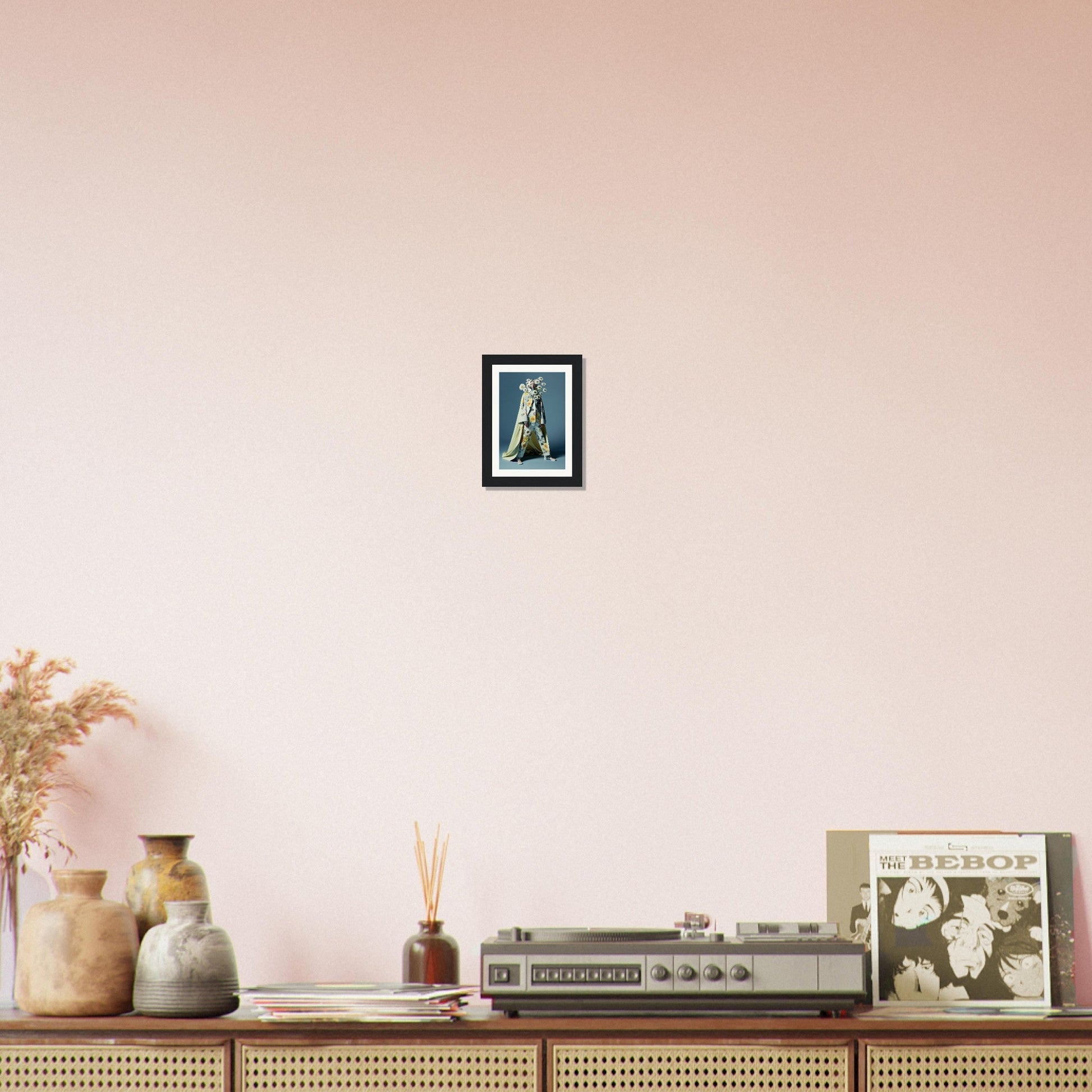 Framed artwork of a blue-green figure hanging on a pale pink wall.