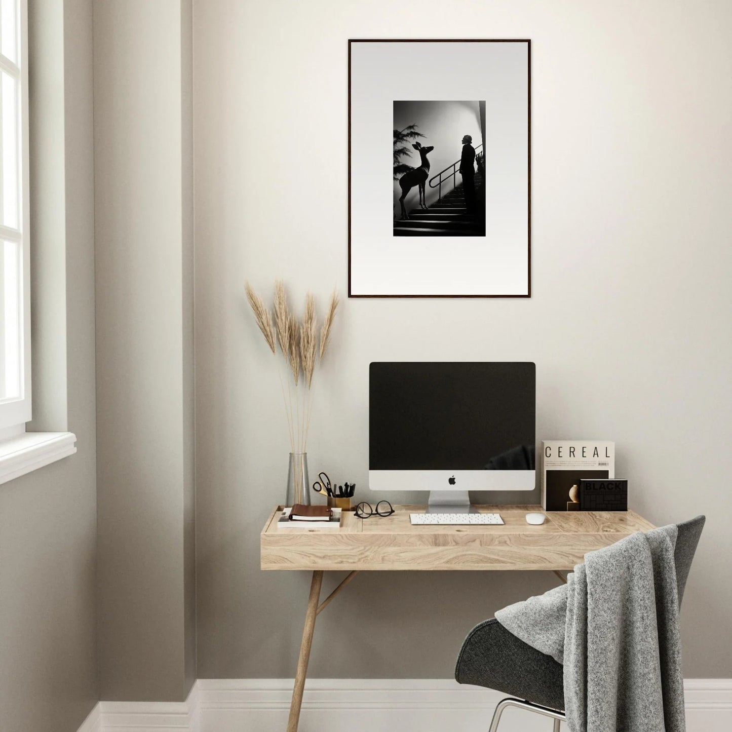 Minimalist wooden desk with a computer monitor and framed artwork above.