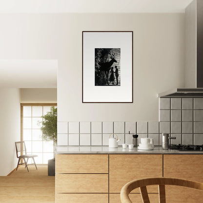 Modern kitchen with wooden cabinetry and a framed black and white photograph on the wall.