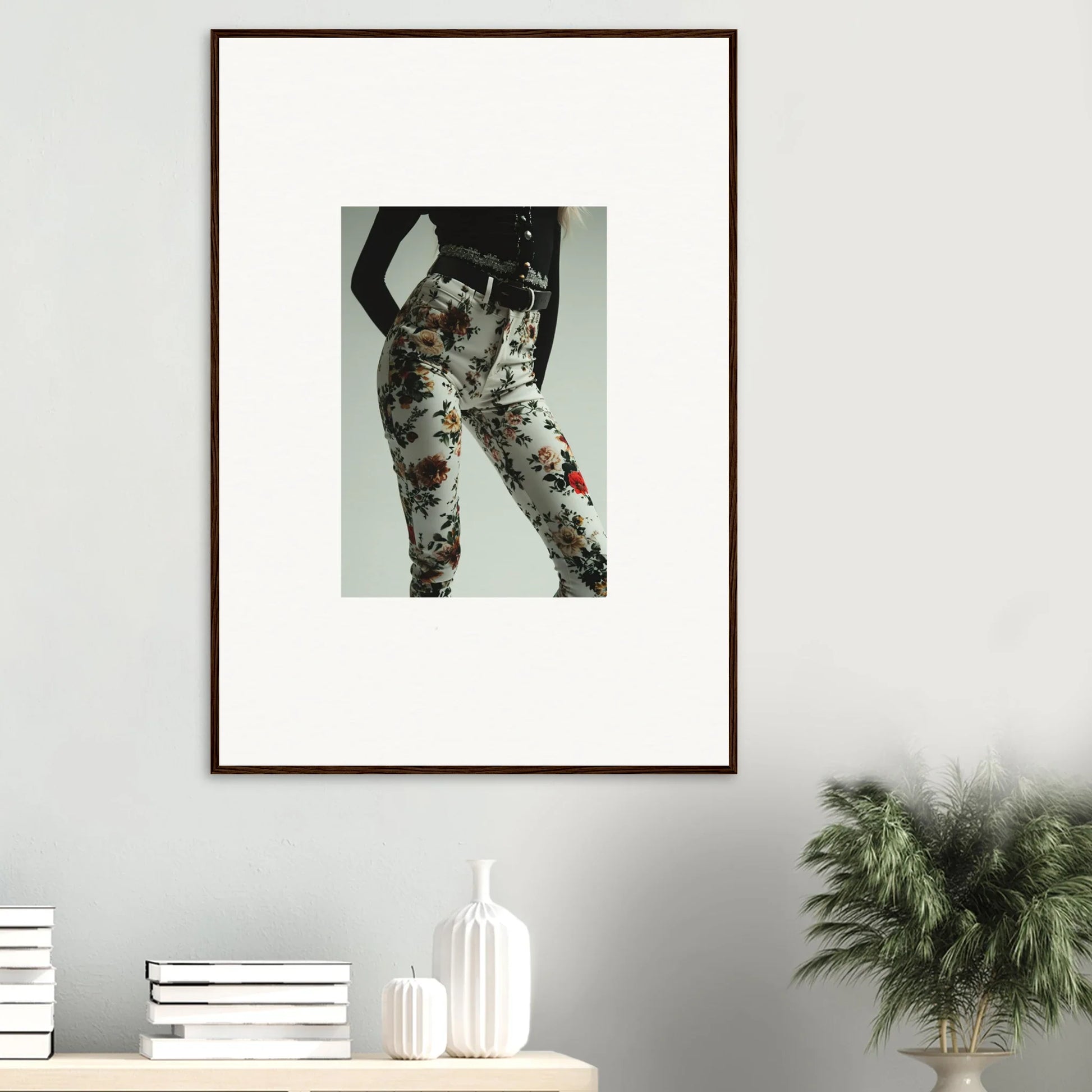 Framed artwork depicting a person’s lower body wearing floral-patterned pants.