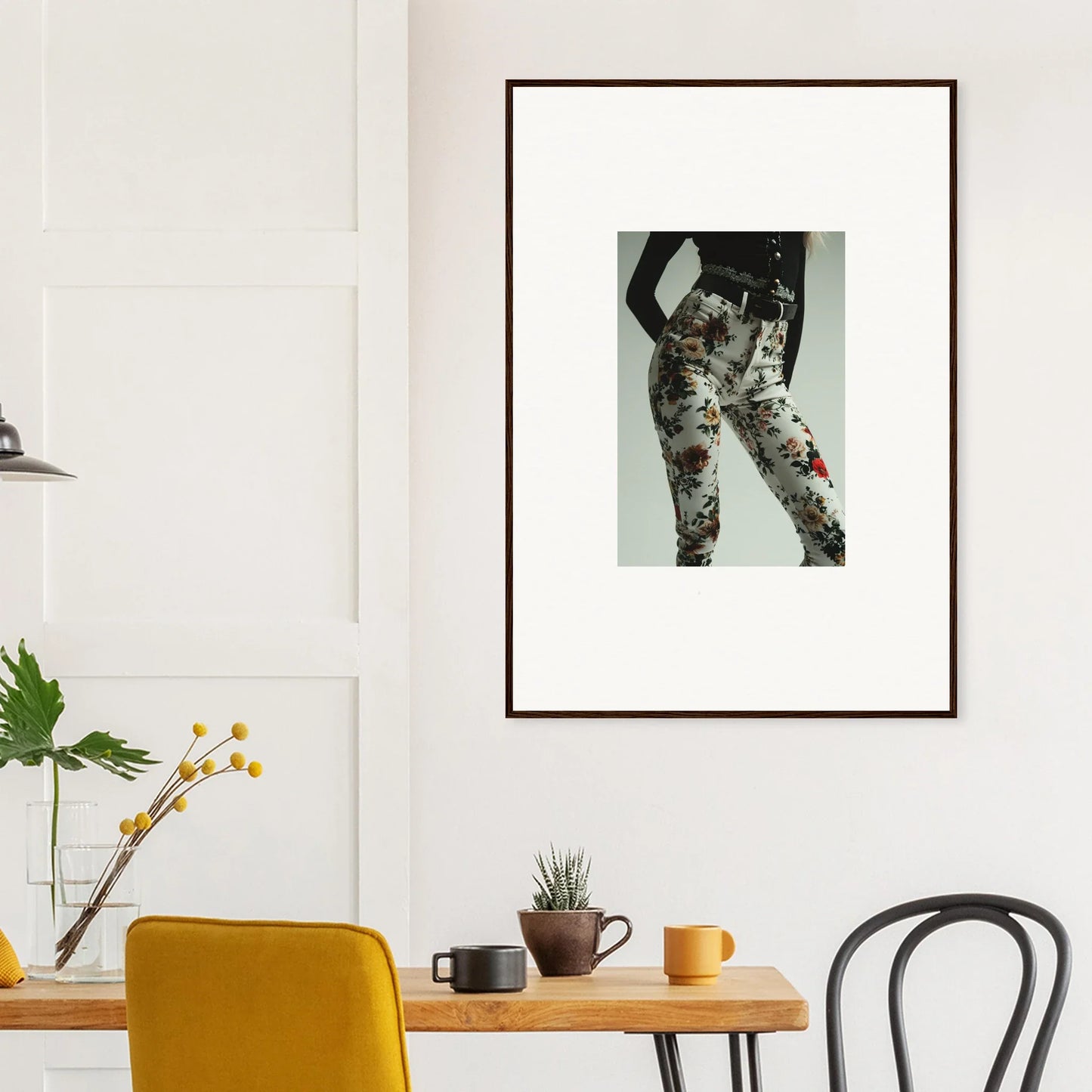 Framed artwork depicting a person’s lower body wearing floral patterned pants.