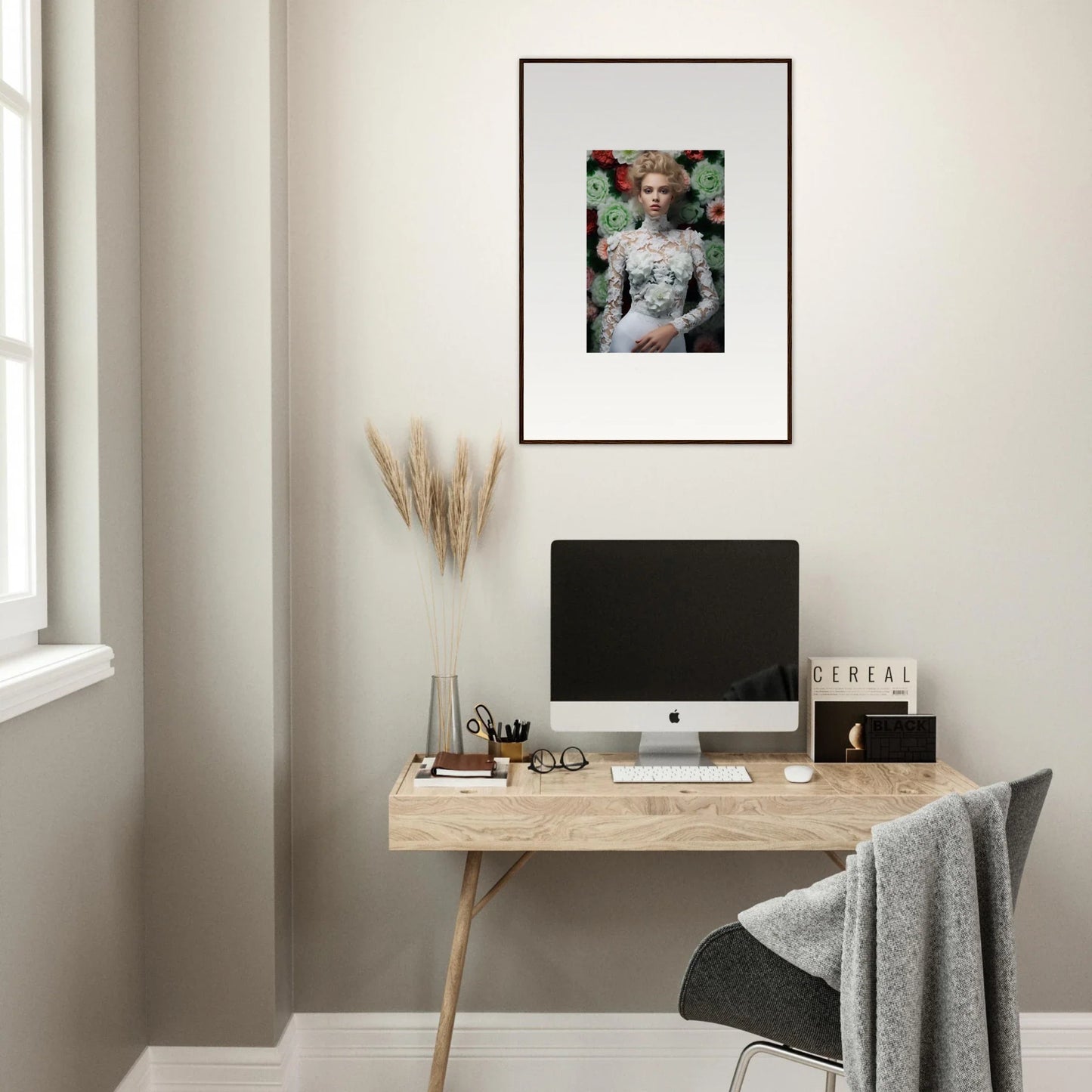 Minimalist home office workspace with a wooden desk, computer, and framed artwork.