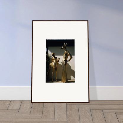 Framed photograph of two people in elegant gold outfits.